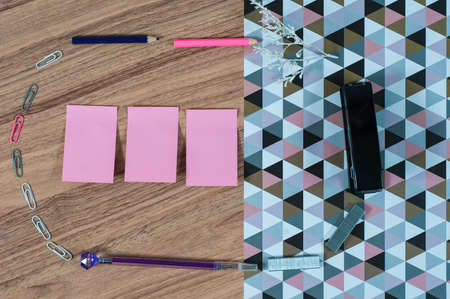 Wooden office table with different stationery, top view. Office worker workplace with pencils, paper, stapler and staplesの写真素材