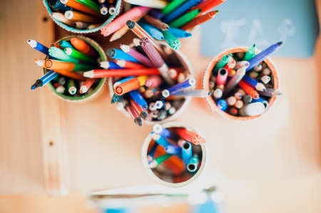 colored glasses with colored pencils on the tableの写真素材