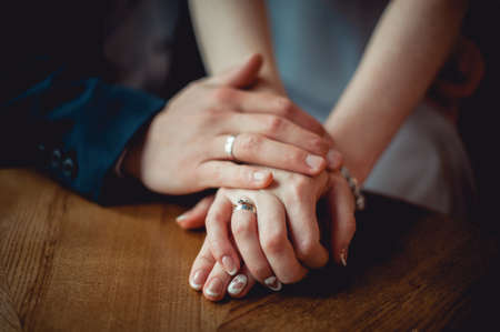 newly married couple hold each other's hands sitting at the tableの写真素材