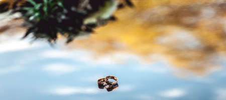 wedding rings on the mirror surface whith sky in itの写真素材