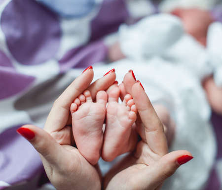 Baby feet in mother and father hands. Tiny Newborn Baby's feet on female Heart Shaped hands closeup. Mom, dad and their Child. Happy Family concept. Beautiful conceptual image of Maternityの写真素材