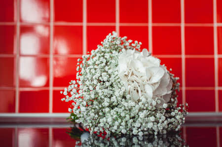 wedding bouquet of white gypsophila on a black table in a front of red tileの写真素材