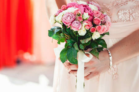 woman in a biege dress holding wedding bouquets of white and biege rosesの写真素材