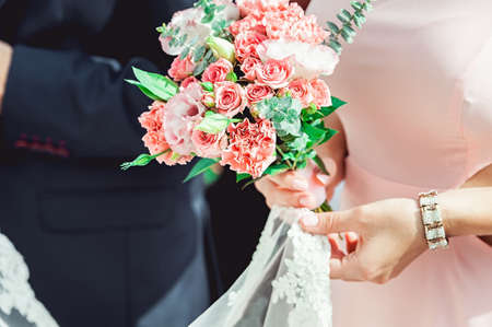 woman in a biege dress holding wedding bouquets of white and biege rosesの写真素材