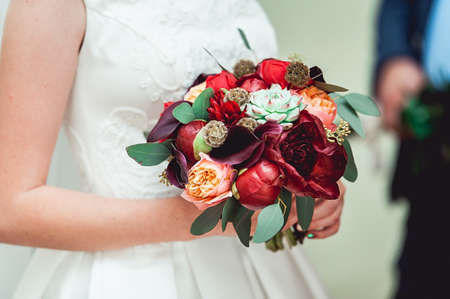 bride in a luxurious wedding dress holding a wedding bouquet made of red roses and peonyの写真素材
