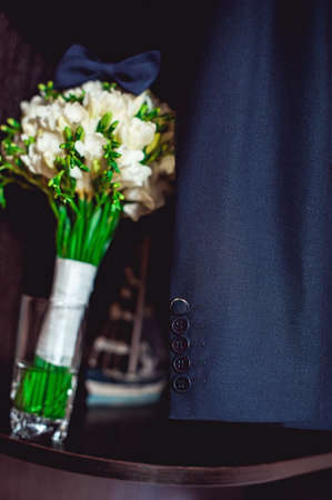 dark blue bow tie on a luxury bridal bouquet of white flowers on a shelfの写真素材