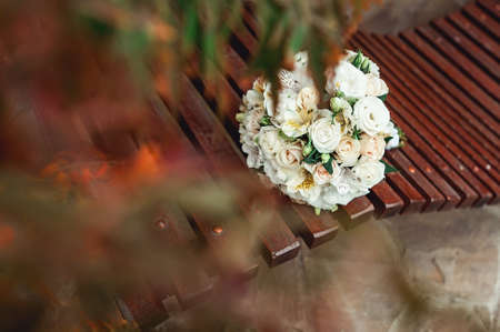 bridal bouquet of white roses with a gold ribbon on a brown benchの写真素材