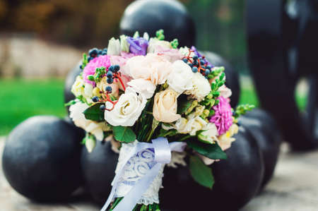 bridal bouquet of different flowers wrapped lace ribbon near bunch of cannonballsの写真素材