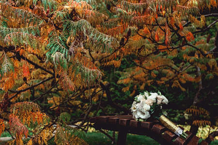 bridal bouquet of white roses with a gold ribbon on a brown benchの写真素材