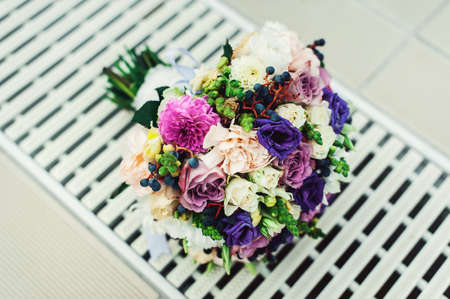 bridal bouquet of different flowers wrapped lace ribbon on a white grid