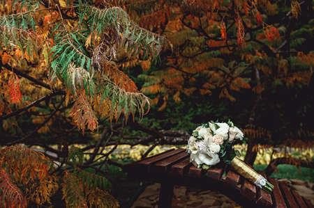 bridal bouquet of white roses with a gold ribbon on a brown benchの写真素材