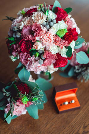 colorful wedding bouquet with roses and carnations on the table next to bridesmaids Boutonniere and box with ringsの写真素材