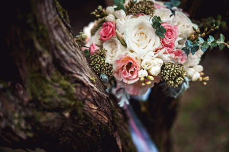 luxurious bridal bouquet of white peonies and roses on the treeの写真素材