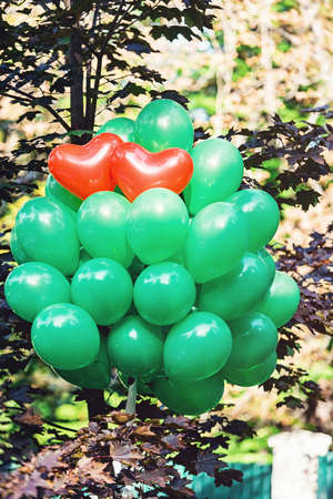 Two red heart baloon surraunded with green baloonsの写真素材