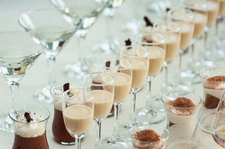 Beautiful row line of different colored alcohol cocktails on a party, Whisky cognac, liquor.の写真素材