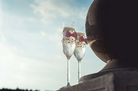 Two wedding champagne glasses with a bow on a stone railing. Lake promenade at sunsetの写真素材