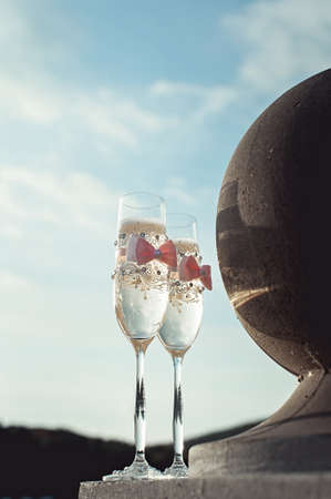 Two wedding champagne glasses with a bow on a stone railing. Lake promenade at sunsetの写真素材