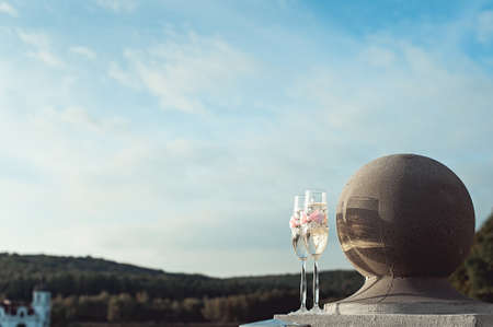 Two wedding champagne glasses with a bow on a stone railing. Lake promenade at sunsetの写真素材