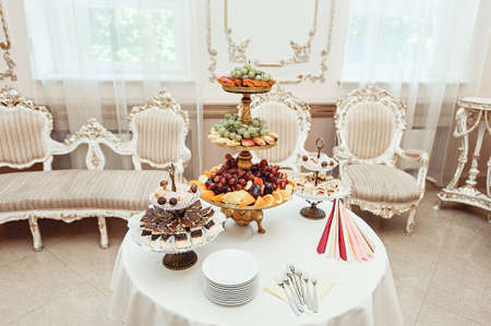 The white restaurant room in vintage style. fruit and pastries on white vintage standsの写真素材
