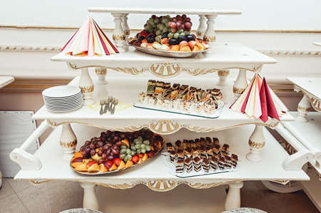 The white restaurant room in vintage style. fruit and pastries on white vintage standsの写真素材