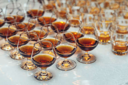Row of glasses with whiskey or cognac on the table. Strong alcohol in a bar or restaurant.の写真素材