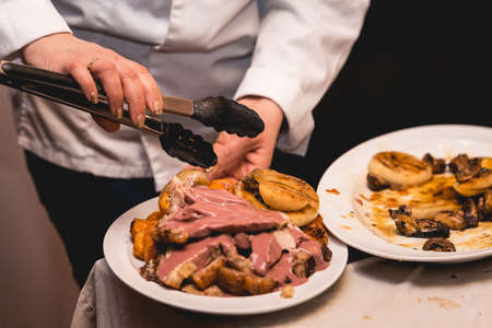 chef cuts roasted meat for restaurant guestsの写真素材