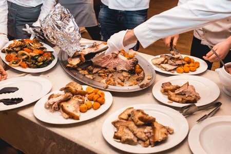 chef cuts roasted meat for restaurant guestsの写真素材