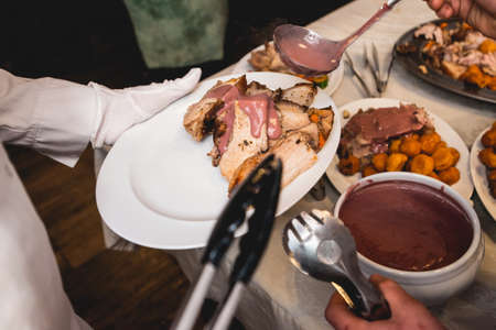 chef cuts roasted meat for restaurant guestsの写真素材