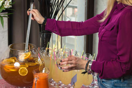 Fresh juice on a table in a restaurant. Healthy drinks. carrot fresh in a jar. Girl pouring juiceの写真素材