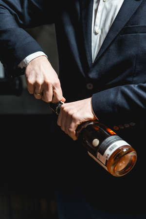 Sommelier in a dark blue jacket opens a bottle of rose wineの写真素材