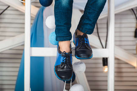 baby sitting on a white wheel wearing blue jeans and black shoes