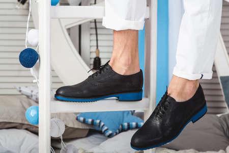 man sitting on a white ladder wearing white jeans and black shoesの写真素材