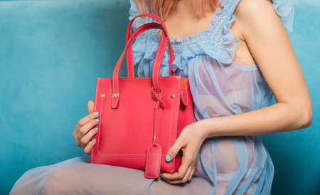 sexy girl in a blue nightgown holds red handbagの写真素材