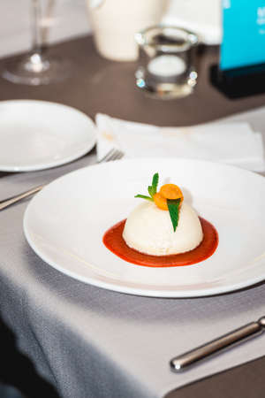 mini round cheesecake with strawberry jam on a plate in the expensive restaurant. close view.の写真素材