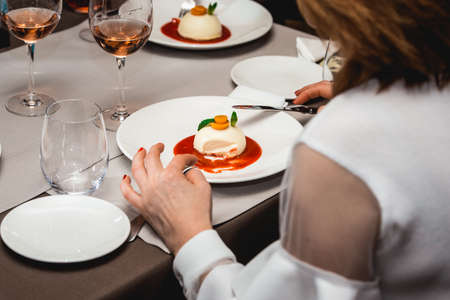 woman is eating cheesecake with strawberry jam on a plate in the expensive restaurant. close viewの写真素材