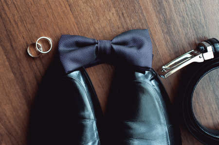 Black bow tie lies before leather shoes and belt. Grooms wedding morningの写真素材