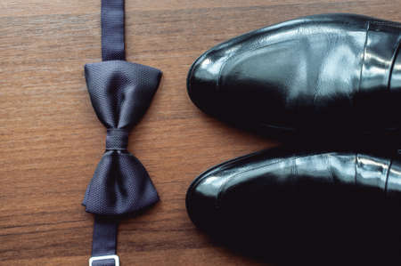 Black bow tie lies before leather shoes and belt. Grooms wedding morningの写真素材