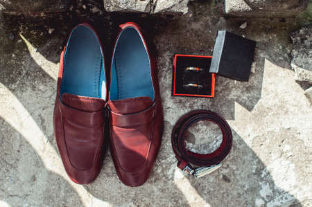 cherry mens shoes, belt and wedding rings in a box. grooms accessories at the wedding dayの写真素材