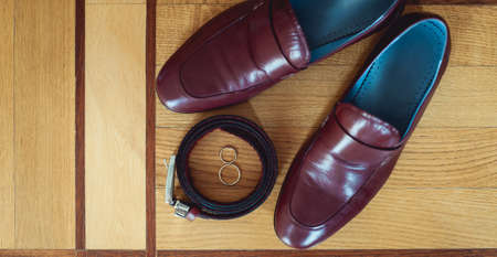 cherry mens shoes, belt and wedding rings in a box. grooms accessories at the wedding dayの写真素材