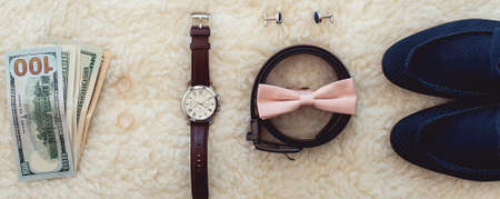 Close up of modern man accessories. Biege bowtie, leather shoes, belt, watch, cufflinks, money and wedding rings.の写真素材