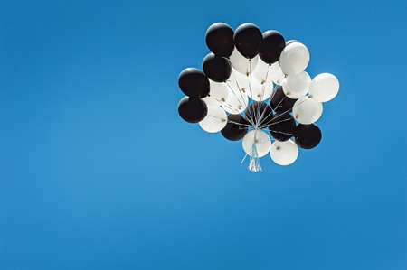 set of black and white balloons high in the sky. cloudless blue skyの写真素材