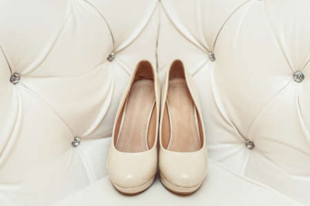 brides biege shoes on heel on a leather vintage sofaの写真素材