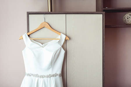Simple white wedding dress on the rack at the wardrobeの写真素材