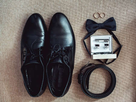 Close up of modern man accessories. wedding rings, black bowtie, leather shoes, belt and cufflinksの写真素材