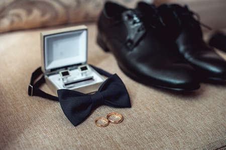 Close up of modern man accessories. wedding rings, black bowtie, leather shoes, belt and cufflinksの写真素材