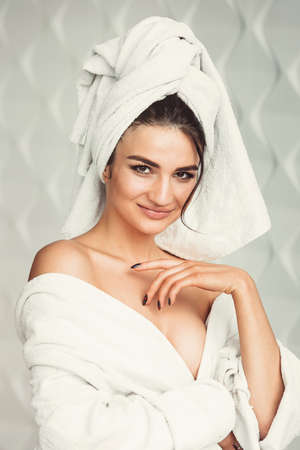 sexy young girl with dark hair, big eyes and dark eyebrows wearing white bath robe whith towel on her head.の写真素材