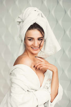 sexy young girl with dark hair, big eyes and dark eyebrows wearing white bath robe whith towel on her head.の写真素材