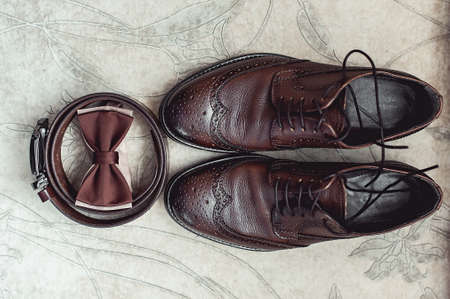 Brown bow tie, leather shoes and belt. Grooms wedding morning. Close up of modern man accessoriesの写真素材