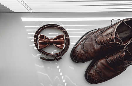 Brown bow tie, leather shoes and belt. Grooms wedding morning. Close up of modern man accessoriesの写真素材