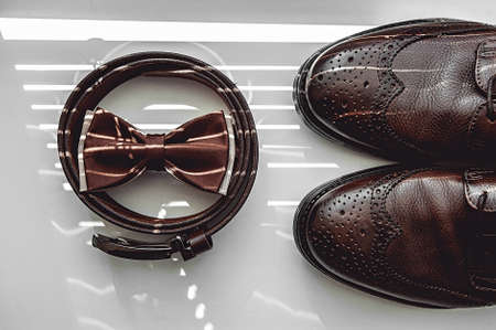 Brown bow tie, leather shoes and belt. Grooms wedding morning. Close up of modern man accessoriesの写真素材